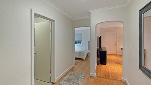 A hallway with a wooden floor, a rug, and a bed in the background. - Welcoming 2-bedroom house 10min walk to the beach in Seaside (Seaside)