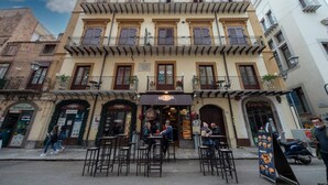 A two-story building with a cafe on the ground floor, outdoor seating, and a sign for 'CANNOLI'. - Casta Diva Luxury Apartments (Palermo)