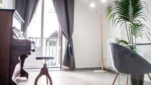 A modern living room with a piano, a chair, a floor lamp, and a potted plant. - Casta Diva Luxury Apartments (Palermo)