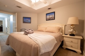 A bedroom with a bed, bedside table, lamp, and two paintings on the wall.