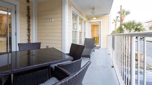 A covered outdoor area with a table and chairs, a door, and a railing.