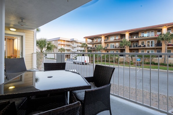 A balcony with a table and chairs, overlooking a street and multi-story buildings.