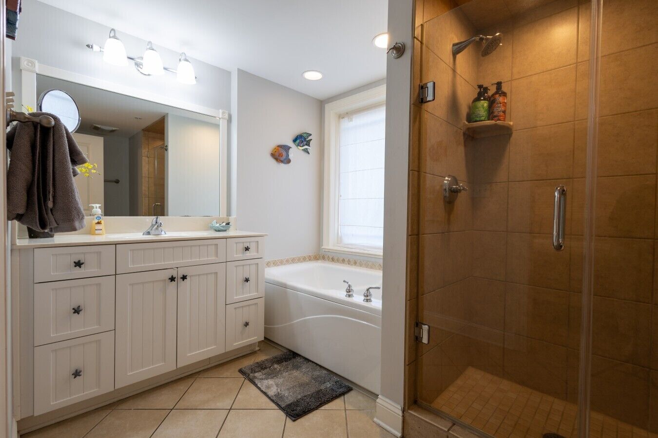 Une salle de bain avec un meuble-lavabo blanc, une baignoire, une douche et une fenêtre.