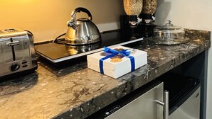 Uma cozinha com micro-ondas, chaleira, torradeira e uma caixa de chocolates no balcão.