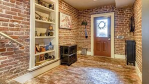 Quarto com paredes de tijolo, escada de madeira e porta decorada com uma coroa de flores.