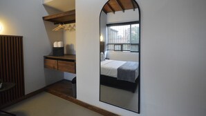 Un dormitorio con cama, cómoda de madera, espejo y ventana.