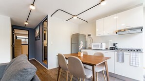 A modern kitchen with white cabinets, a wooden dining table, and a gray sofa in the living area. - VH | Condesa | Natural Light + Balcony & Gym | 250 (Ciudad de México)