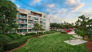 A multi-story hotel with balconies, a swimming pool, and a well-maintained lawn.