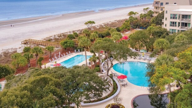 A resort with a large pool area, a beach view, and a building with balconies.