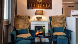 Ein gemütlicher Raum mit zwei bequemen Sesseln, einem Kamin und einem Schild mit der Aufschrift 'HOTEL PRINCESS'.