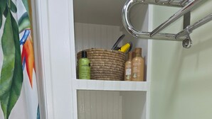 Un baño con cortina de ducha, un estante con artículos de aseo y un cartel con una cita de una sirena.