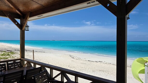 Vista a la playa desde una estructura de madera con un área de estar cubierta.