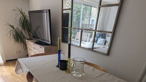Un comedor con una mesa preparada para dos personas, un televisor y una ventana que ofrece vistas al exterior.