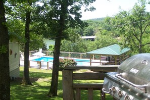 A backyard with a swimming pool, a barbecue grill, and a covered picnic area.