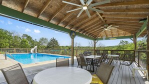 Un espace extérieur abrité comprenant une piscine, des sièges et un ventilateur de plafond.