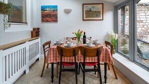 Una sala da pranzo con un tavolo imbandito per quattro persone, una finestra a lucernario e due quadri alle pareti.