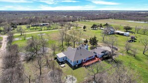 A large house with a spacious backyard, a pond, and a clear view of the surrounding landscape.