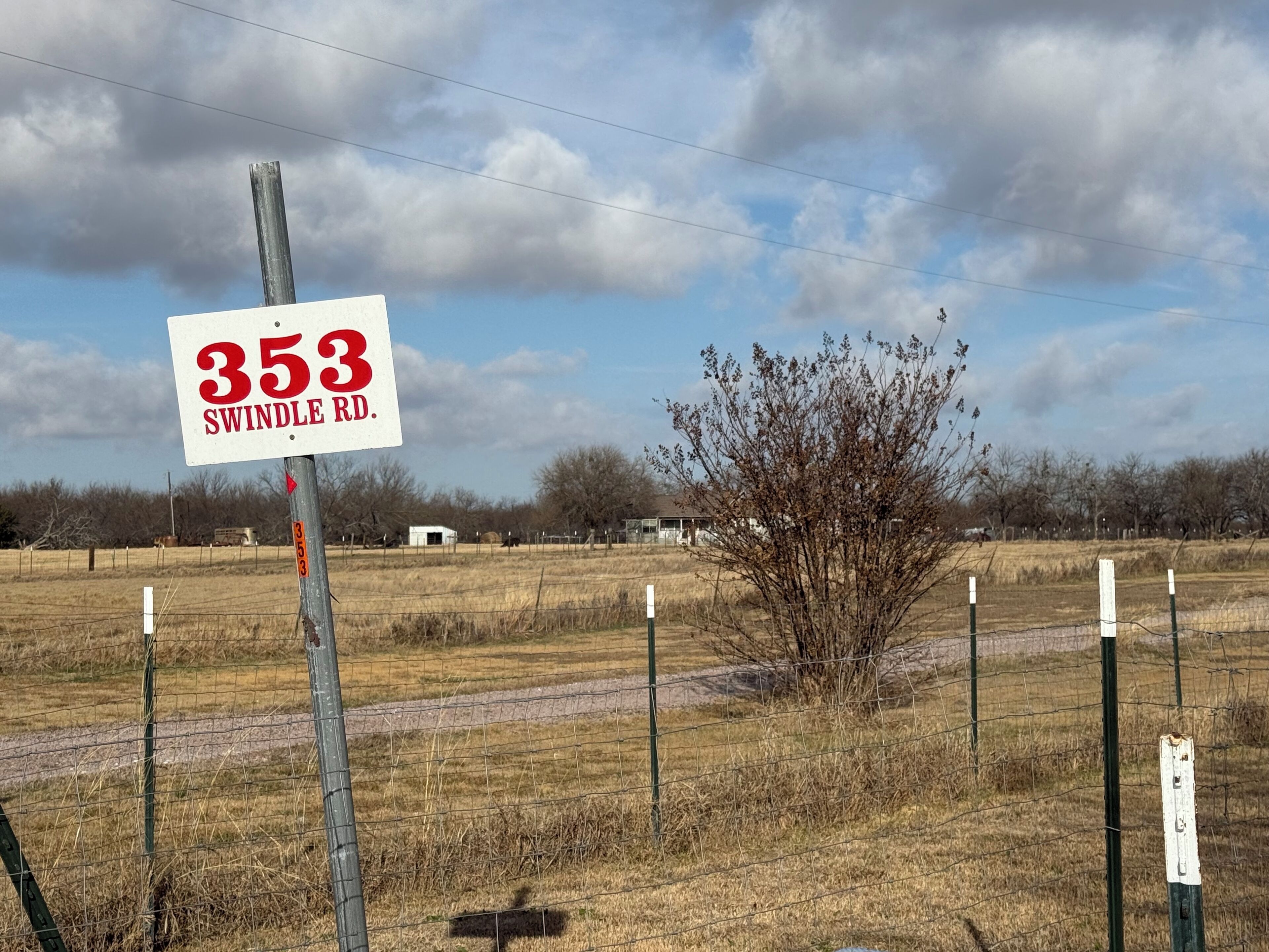 A rural landscape with a sign reading "353 SWINDLE RD."