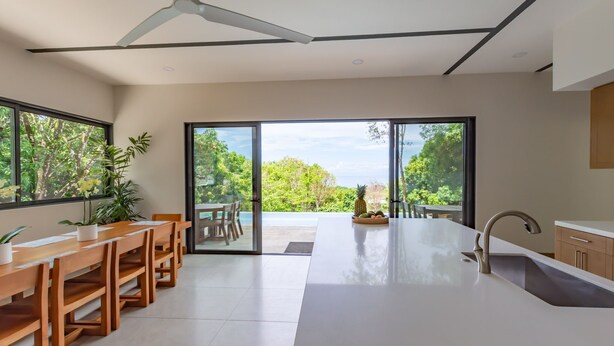 A modern kitchen with a large island, sliding glass doors to a patio, and a ceiling fan.