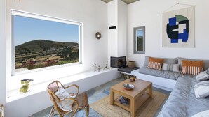 A modern living room with a large window, a sofa set, a wooden coffee table, and a wicker chair.