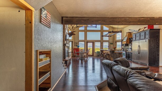 A spacious living area with a leather sofa, wooden shelves, and a large window offering a view of the outdoors. - Breathtakingly charming 4-bedroom house with WiFi in Charlo. (Charlo)