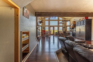 A spacious living area with a leather sofa, wooden shelves, and a large window offering a view of the outdoors. - Breathtakingly charming 4-bedroom house with WiFi in Charlo. (Charlo)