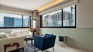 A modern living room with a sofa, armchair, and a small table with a vase of flowers. - Sleek High-Rise with Pool, Gym, Jacuzzi & BBQ Area (Mexico City)
