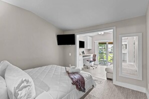 A bedroom with a bed, a flat-screen TV, a desk, and a chair.