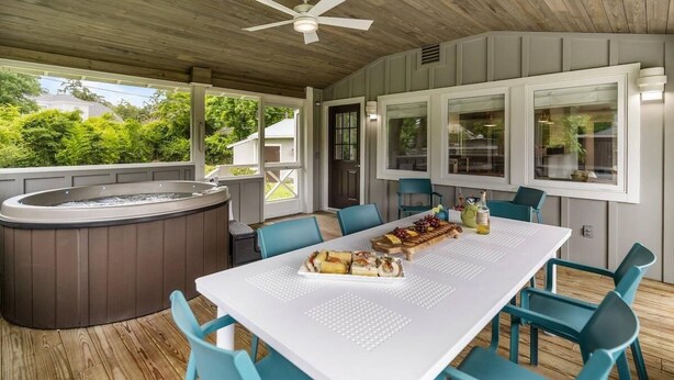 A covered outdoor dining area with a hot tub, a table set for a meal, and a ceiling fan. - Serenity on Trinity - Hot Tub - Pets Welcome (Wilmington)