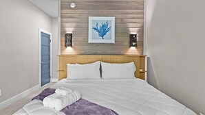 A bedroom with a bed, a blue door, a wooden headboard, and a framed artwork on the wall. - Serenity on Trinity - Hot Tub - Pets Welcome (Wilmington)