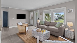 Un salon avec un canapé, un fauteuil, une table basse et un téléviseur.