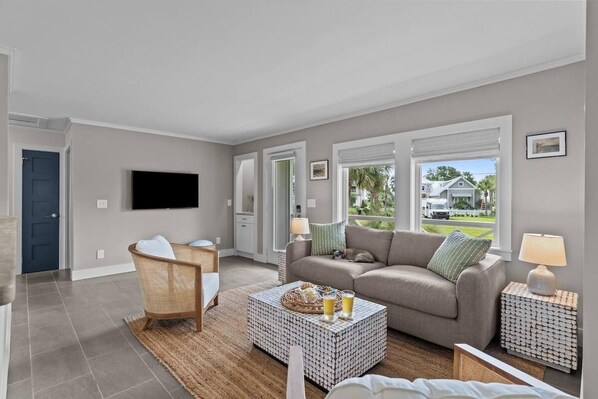 A living room with a sofa, a chair, a coffee table, and a TV.