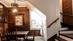 A dining area with wooden walls, a chandelier, and a staircase. - Little Noone by Raven’s Keep (Jackson)