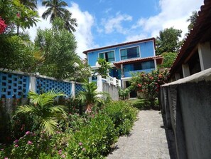 A pathway leading to a building with a blue facade and a tiled roof. - Pousada Vila Anauá (Japaratinga)