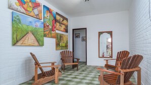 Une pièce avec quatre fauteuils à bascule en bois, un sol à carreaux verts et blancs et plusieurs tableaux accrochés au mur.