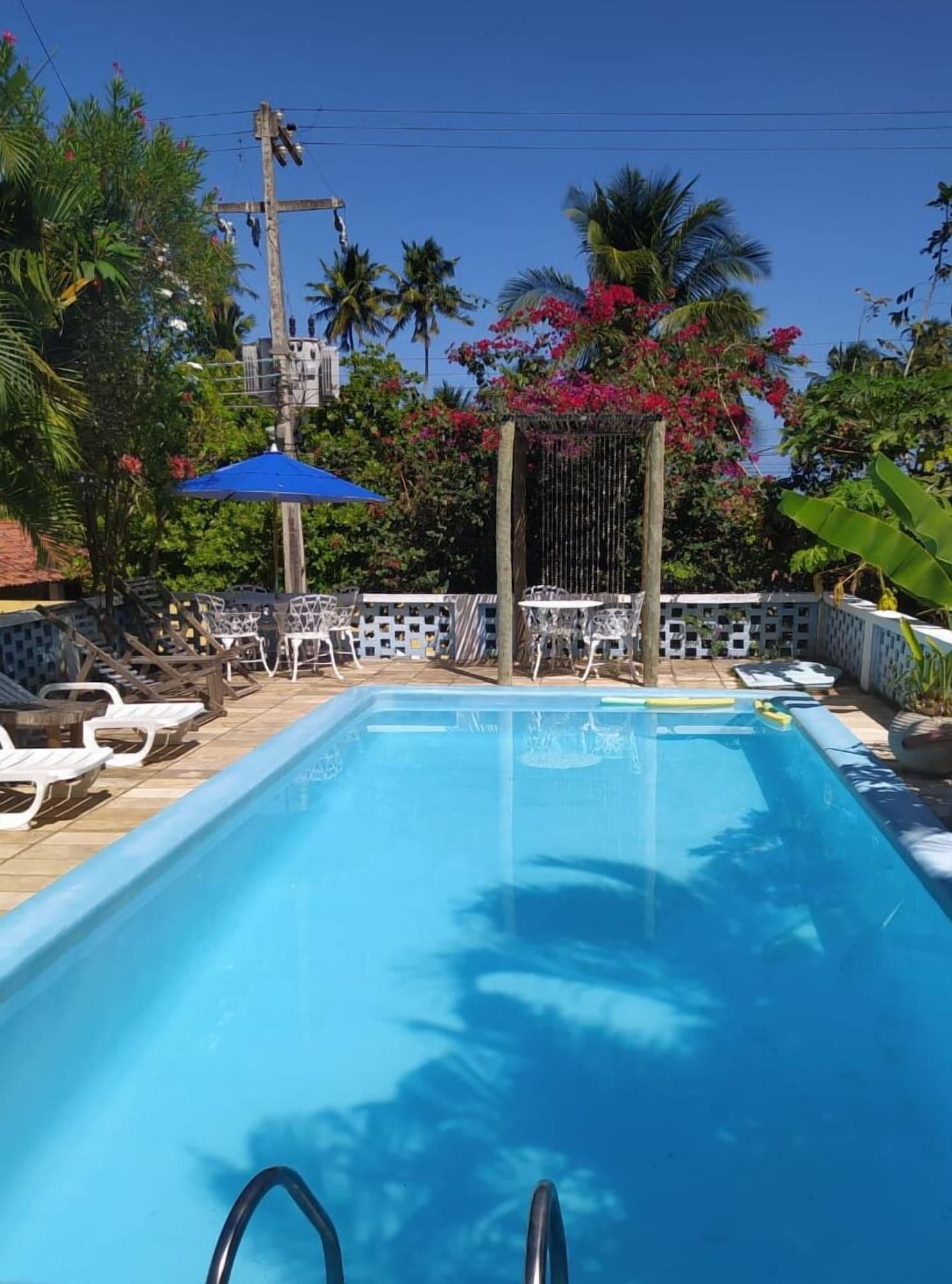 A swimming pool with lounge chairs and a covered seating area.