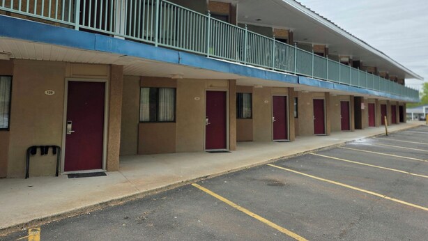 A motel with a row of rooms, each with a door and a window.