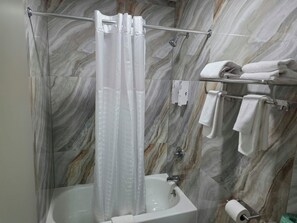 A bathroom with a shower curtain, a bathtub, a towel rack with towels, and a toilet paper holder. - Red Roof Inn Green Brook - Somerset (Green Brook)
