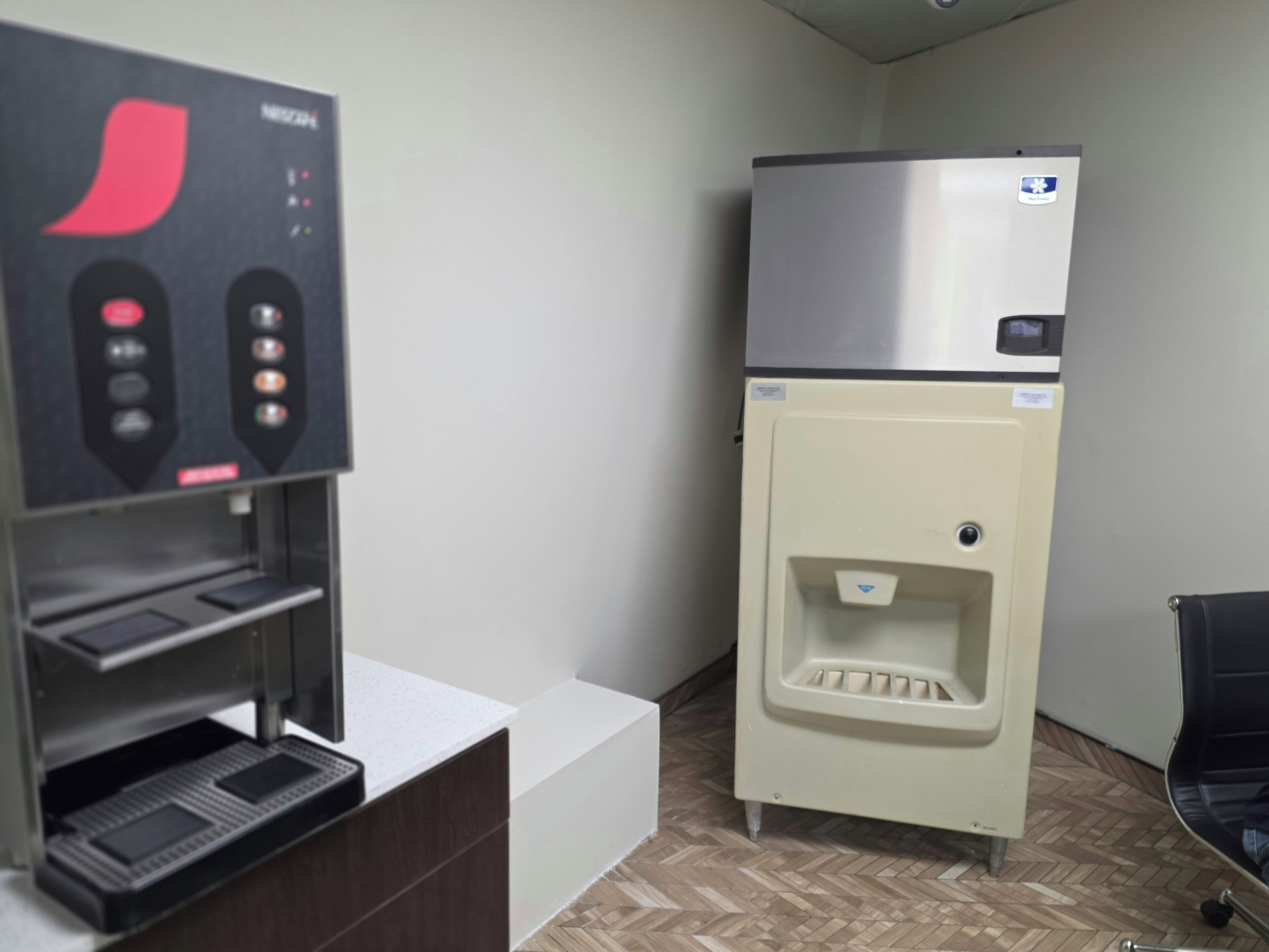 Una habitación con máquina expendedora, refrigerador y dispensador de agua.