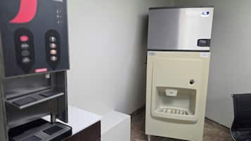 Una habitación con máquina expendedora, refrigerador y dispensador de agua.