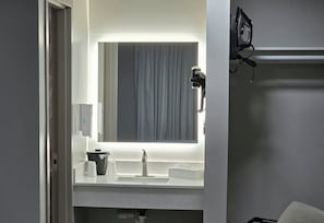 A bathroom with a mirror, sink, and a hairdryer on the counter. - Red Roof Inn Green Brook - Somerset (Green Brook)
