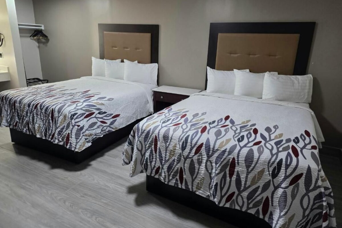 Dos camas individuales con cabeceras, una mesita de noche y un calentador de pared.