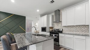 Et moderne køkken med hvide skabe, en granitbordplade og rustfrie stålgre.