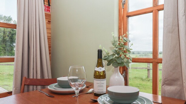 Ett matbord dukat med tallrikar, en vinflaska, ett glas och en vas med blommor.
