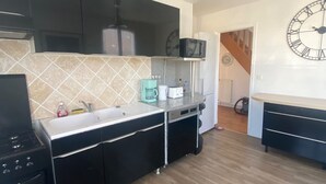 A modern kitchen with black cabinets, a microwave, a coffee maker, and a clock on the wall.
