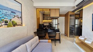 Una cocina compacta con electrodomésticos modernos, un comedor con dos sillas y un sofá.