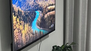 Un téléviseur à écran plat fixé au mur, qui diffuse une image d’un paysage pittoresque.