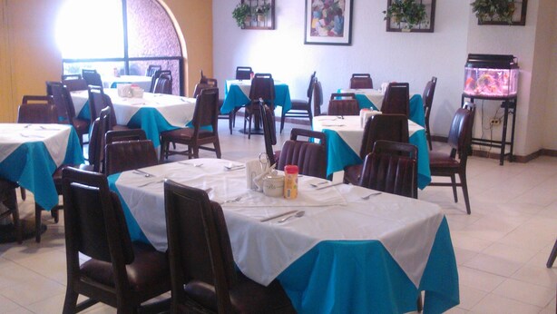 A dining area with tables covered in white tablecloths and blue table runners, arranged in rows with chairs. - Hotel y Restaurante Ritz de Tabasco (Villahermosa)