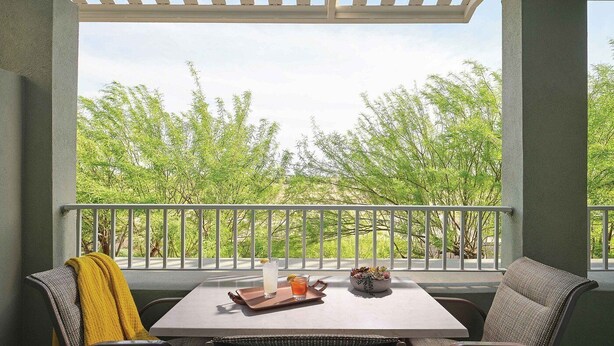 Un espace extérieur abrité, aménagé avec une table, des chaises et une rambarde.