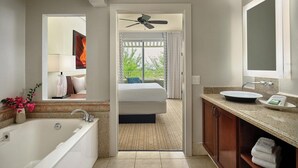 Une salle de bain moderne avec une baignoire, un grand miroir, un ventilateur de plafond et une vue sur un balcon.